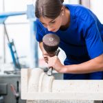 woman Stonemason carving pillar out of stone in workshop