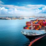 Aerial side view of cargo ship carrying container and running fo
